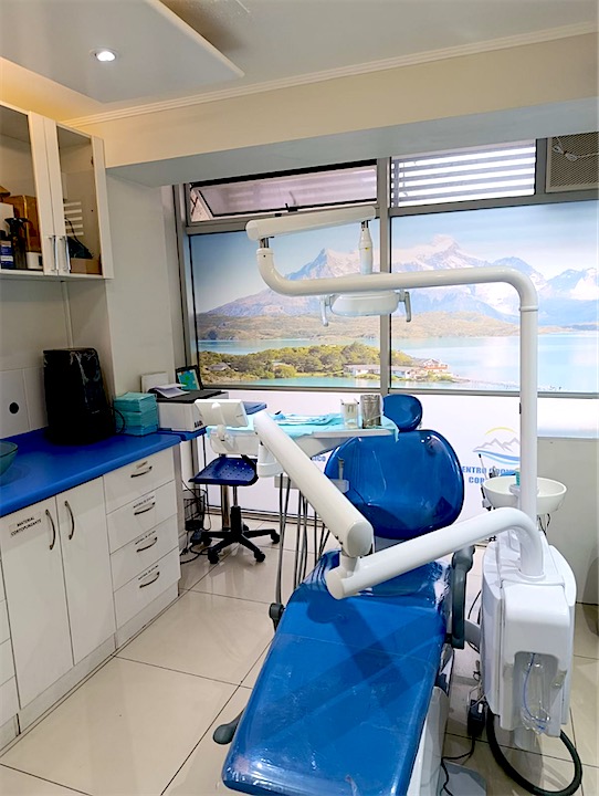 Box dental con sillón azul y un mural de la cordillera en la ventana