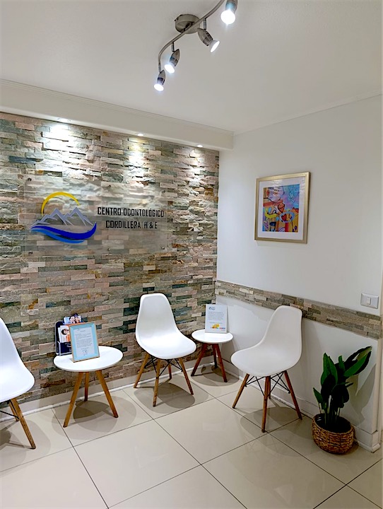 Sala de espera del Centro Odontológico Cordillera, con el logo sobre un muro de piedra